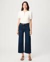 Woman wearing a white top and dark blue jeans on a white background