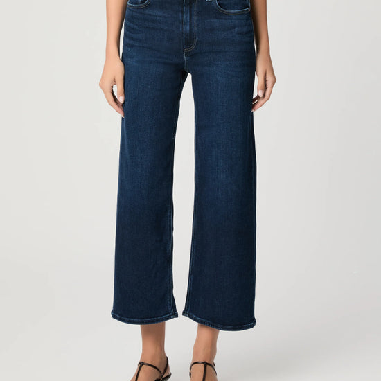 Person wearing dark blue wide-leg jeans on a white background