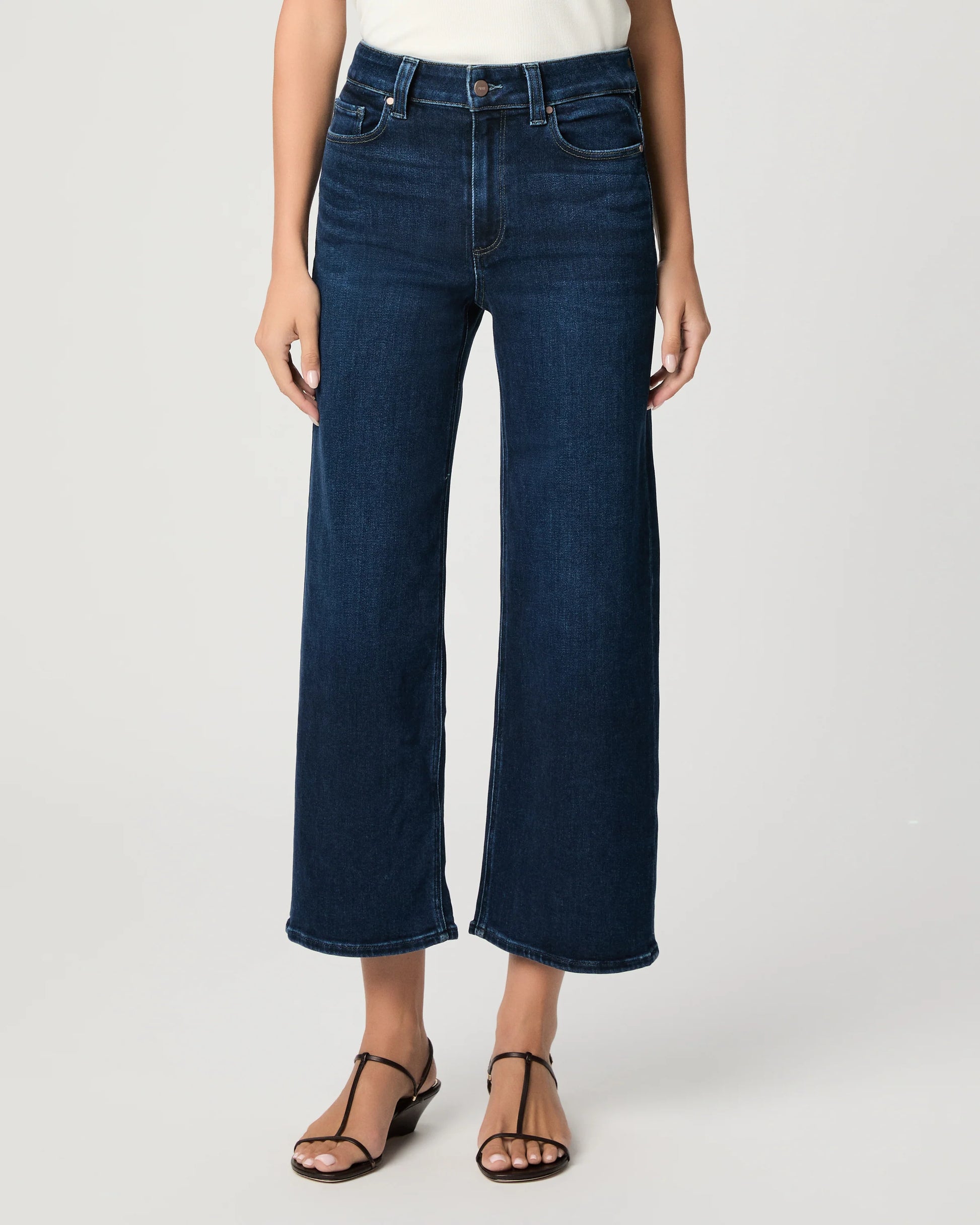 Person wearing dark blue wide-leg jeans on a white background