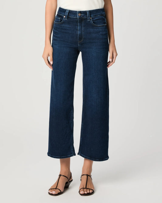 Person wearing dark blue wide-leg jeans on a white background