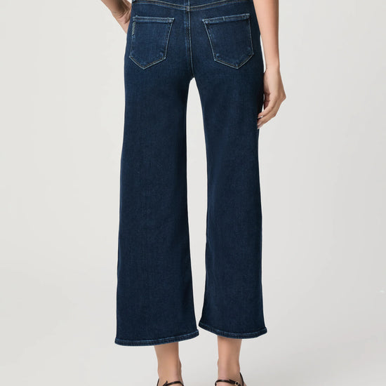 Person wearing dark blue wide-leg jeans on a white background