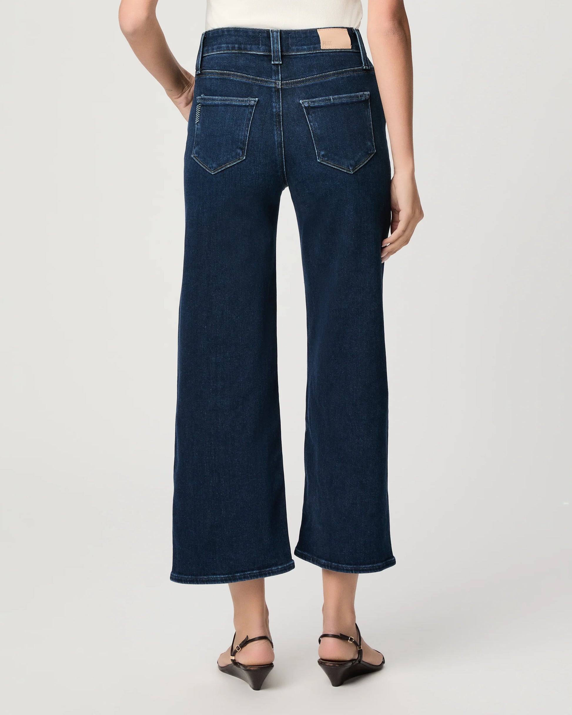 Person wearing dark blue wide-leg jeans on a white background