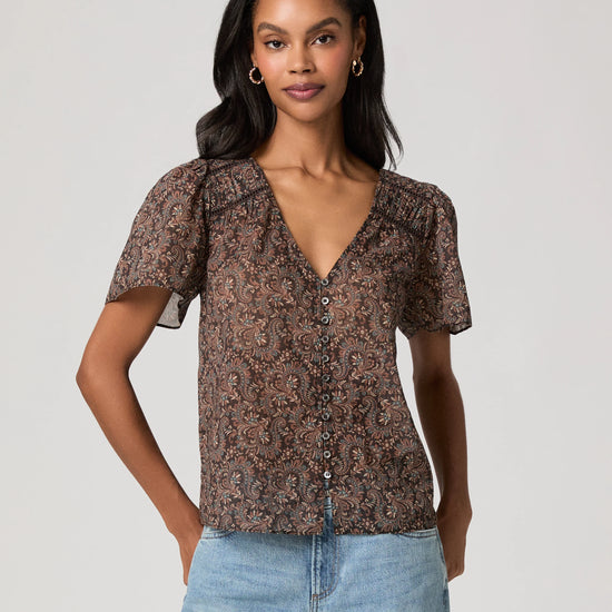 woman wearing a brown paisley blouse and jeans