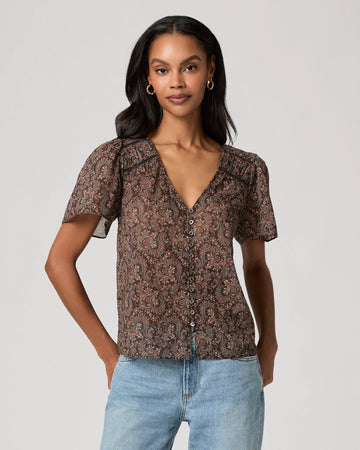woman wearing a brown paisley blouse and jeans