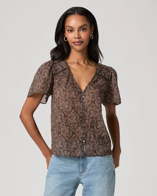 woman wearing a brown paisley blouse and jeans