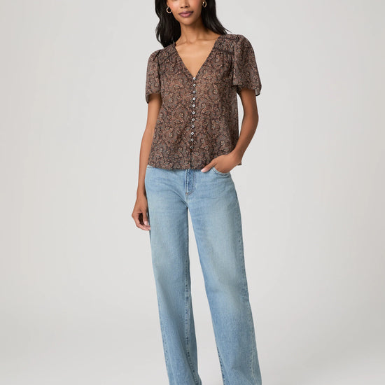 woman wearing a brown paisley blouse and jeans full outfit shot