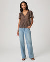 woman wearing a brown paisley blouse and jeans full outfit shot