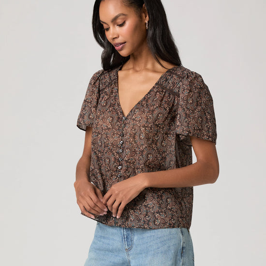 woman wearing a brown paisley blouse and jeans side view