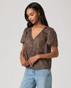 woman wearing a brown paisley blouse and jeans side view