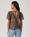 woman wearing a brown paisley blouse and jeans rear view