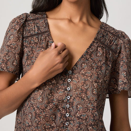 woman wearing a brown paisley blouse close up