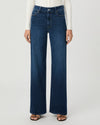 A model wearing dark blue wide-leg denim jeans, a white ribbed long-sleeve top, and brown sandals, shown from the waist down against a light gray studio background.