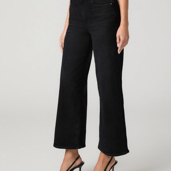 A model wearing black wide-leg cropped jeans with a ribbed top and black slingback heels, shown from the waist down against a light gray studio background.