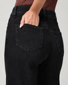 Close-up back view of a person wearing black high-waisted jeans, with one hand tucked into the back pocket, against a light gray background.