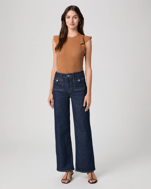 Woman wearing a brown top and dark blue jeans on a white background