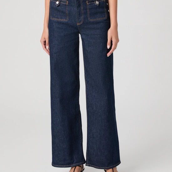 Person wearing dark blue wide-leg jeans on a white background