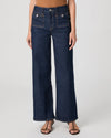 Person wearing dark blue wide-leg jeans on a white background