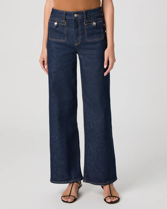 Person wearing dark blue wide-leg jeans on a white background