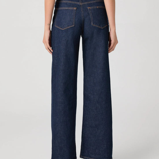 Person wearing dark blue wide-leg jeans on a light gray background