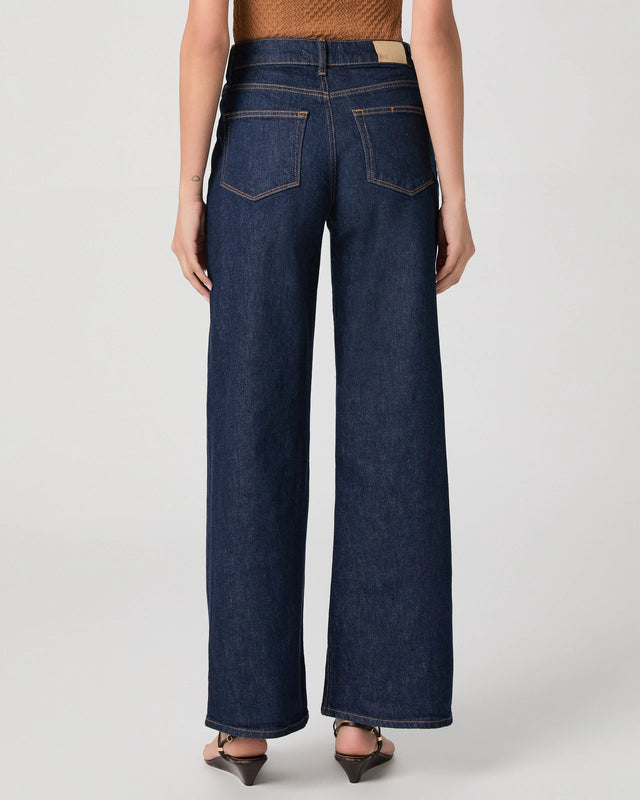Person wearing dark blue wide-leg jeans on a light gray background