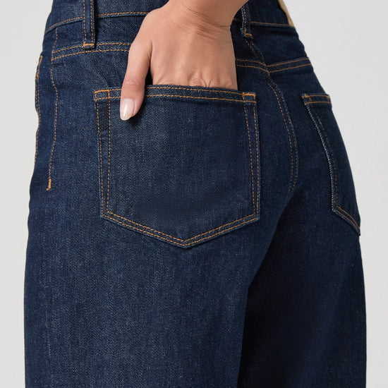 Close-up of dark blue jeans with a pocket, on a plain background