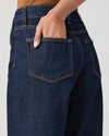 Close-up of dark blue jeans with a pocket, on a plain background