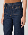 Dark blue jeans worn by a person on a plain background