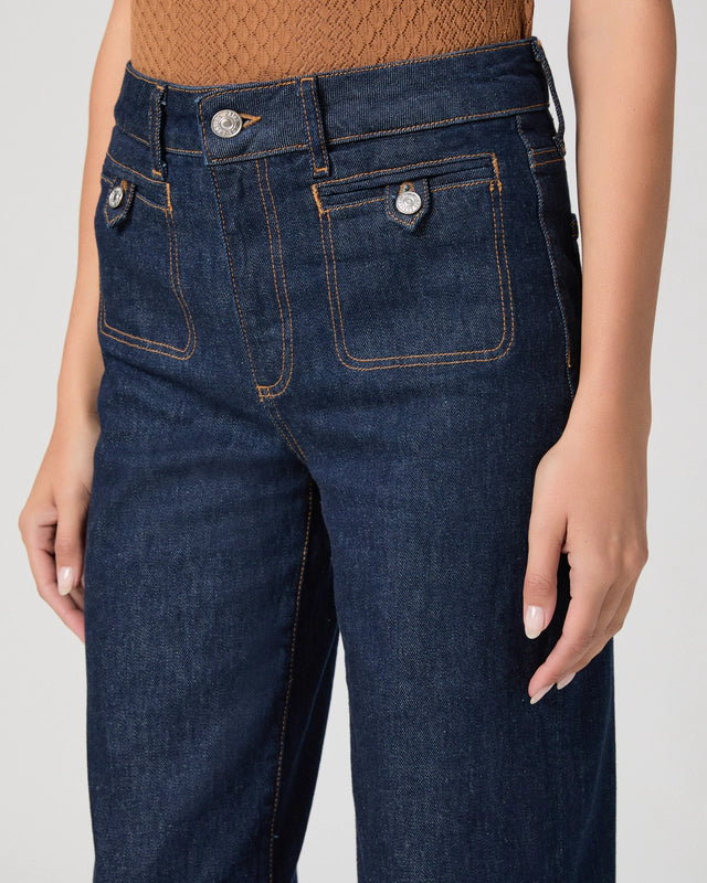 Dark blue jeans worn by a person on a plain background