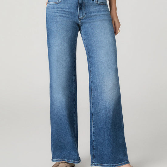 Model wearing blue jeans on a grey background