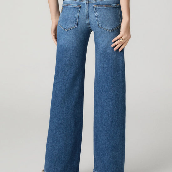 Model wearing blue jeans on a grey background rear view