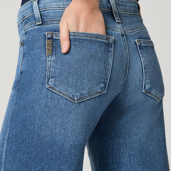 Model wearing blue jeans on a grey background close up