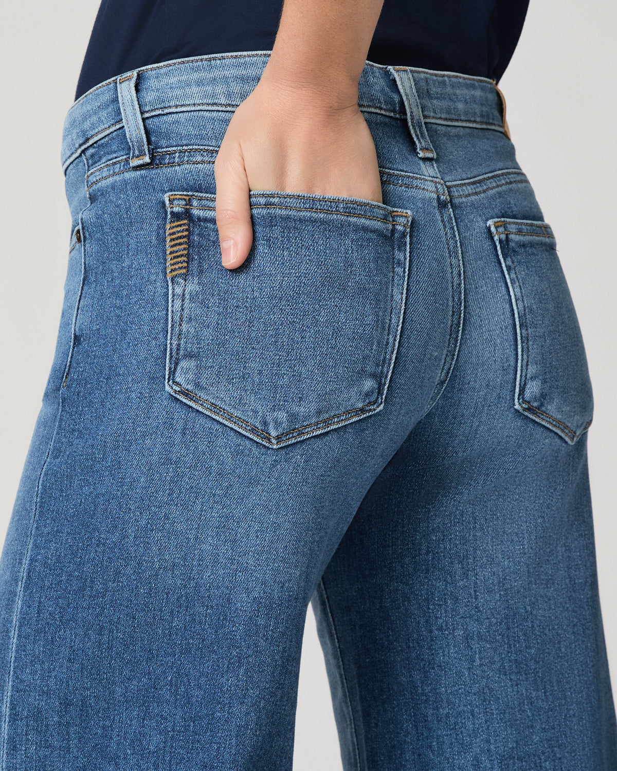 Model wearing blue jeans on a grey background close up