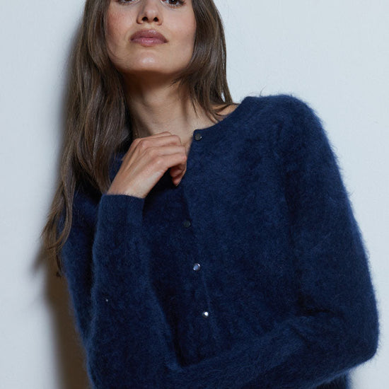 Woman wearing a navy blue cardigan against a plain background