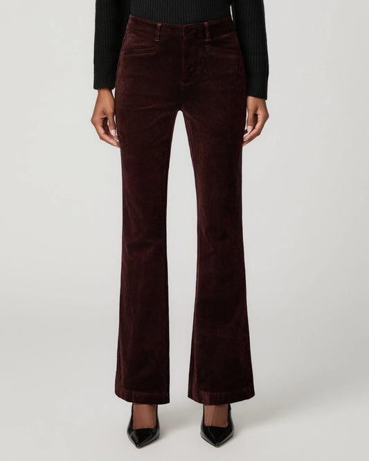 A model is shown from the waist down wearing dark brown corduroy flare pants, a black ribbed long-sleeve top, and black pointed-toe heels against a light gray studio background.
