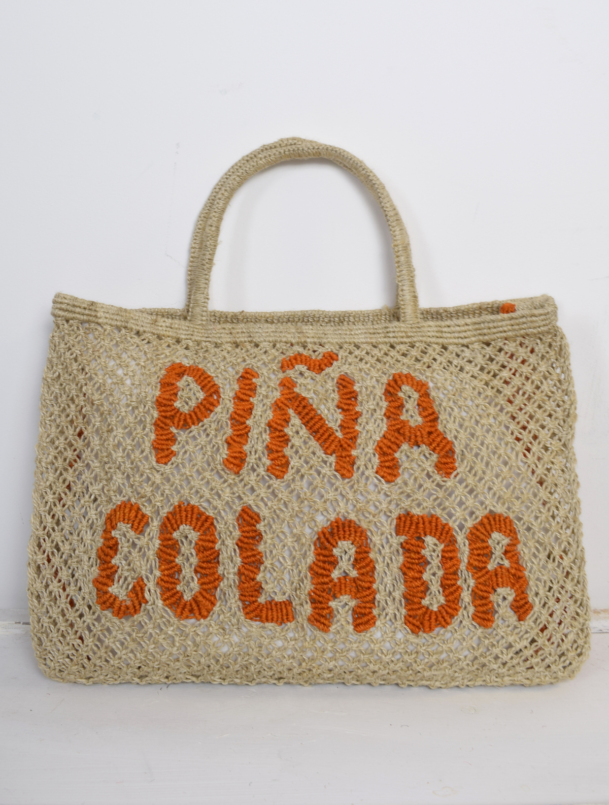Woven nautral bag with pina colada writen on it in orange 