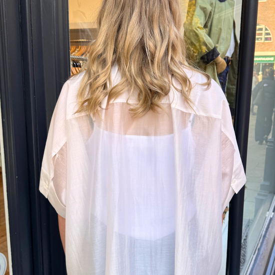 Person wearing a sheer white blouse and blue jeans