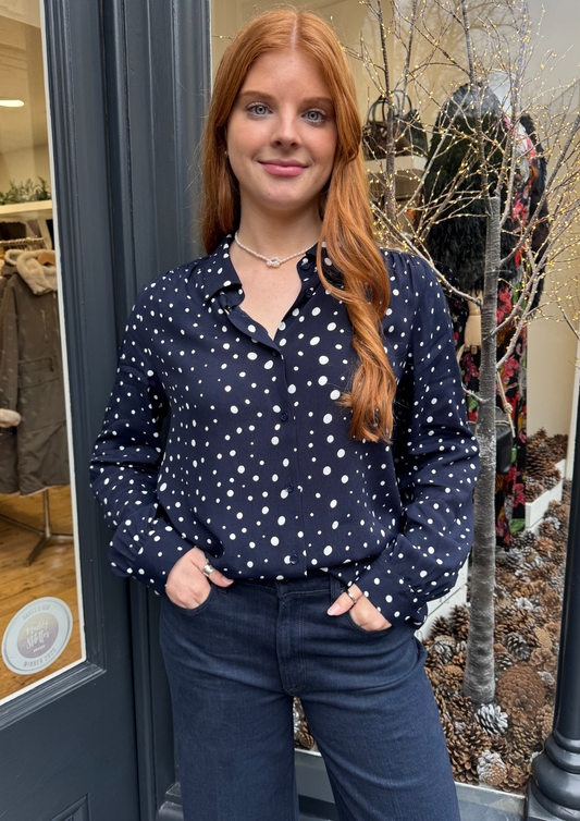 Navy long sleeved shirt with different sized white dots, styled with dark denim