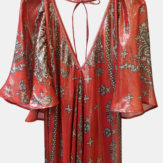 Red and gold patterned dress on a hanger against a white background