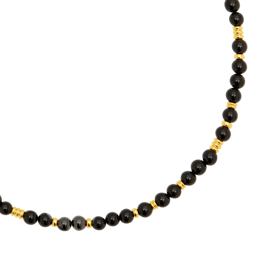 A beaded necklace featuring glossy black round beads separated by small gold spacers, displayed on a clean white background.