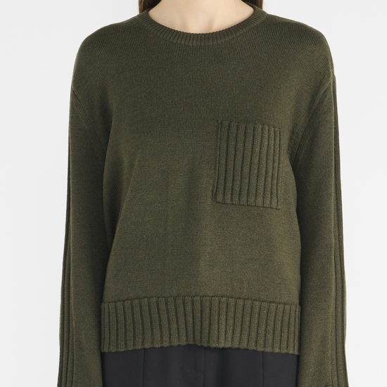 Dark green jumper with round neck, with chest patch pocket and ribbed hem and cuffs. Close up.