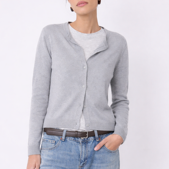 Woman wearing a cashmere gray cardigan, white shirt, blue jeans, and sunglasses on a light gray background from Not Shy