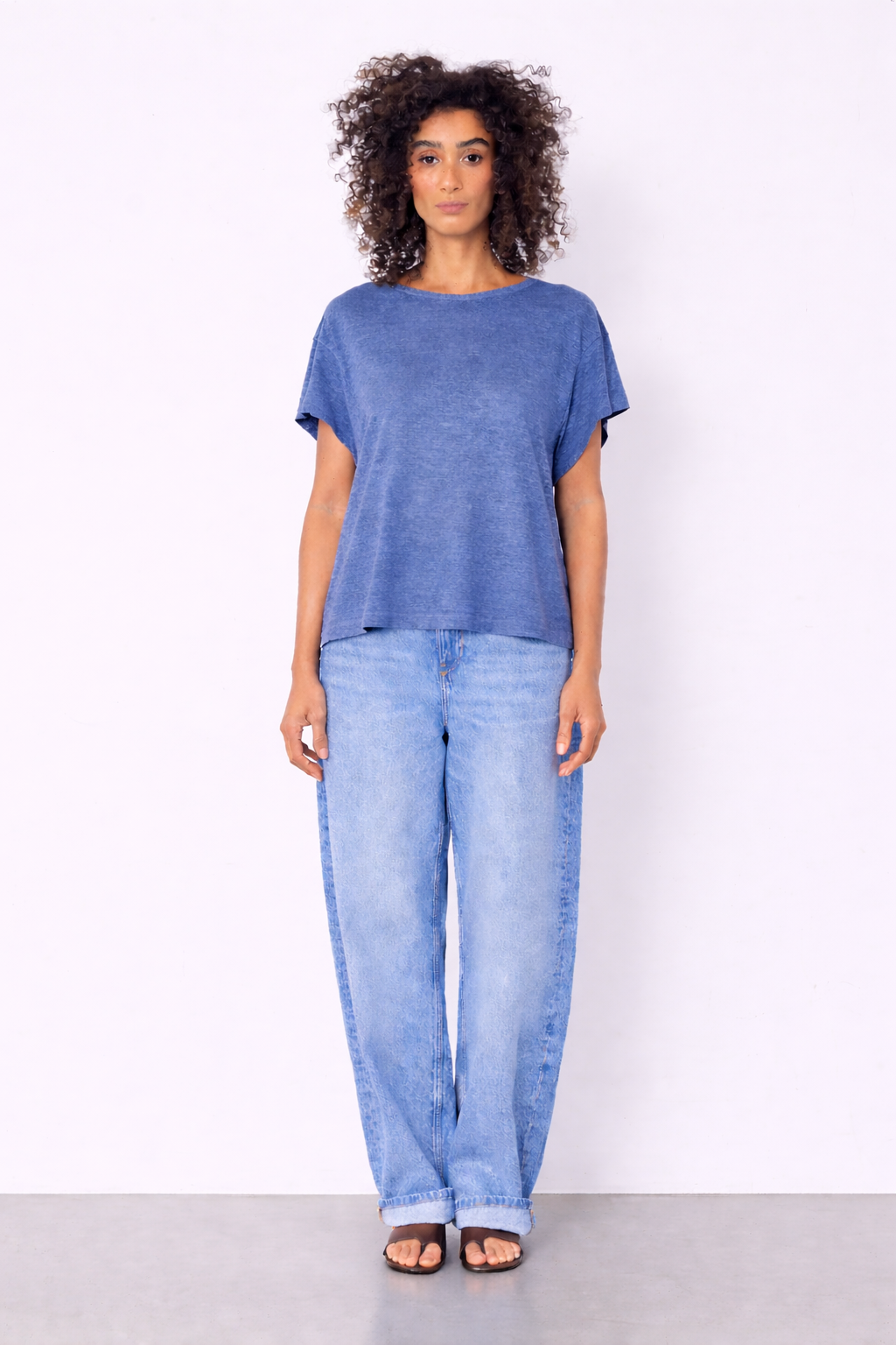 blue top and jeans on model on plain background
