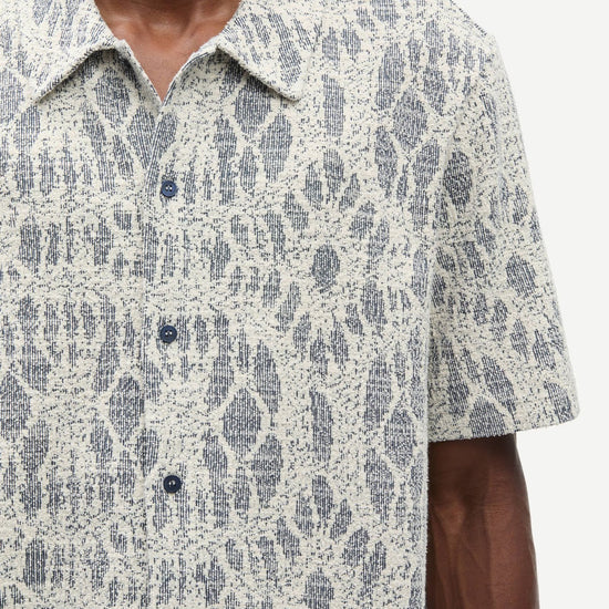 Man wearing a patterned shirt by samsoe samsoe with a neutral background