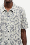 Man wearing a patterned shirt by samsoe samsoe with a neutral background