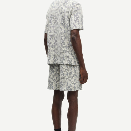 Man wearing a patterned shirt and shorts set by samsoe samsoe on a white background rear view