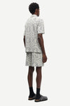 Man wearing a patterned shirt and shorts set by samsoe samsoe on a white background rear view
