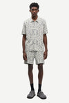 Man wearing a patterned shirt and shorts set by samsoe samsoe on a white background