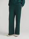A person wearing dark teal wide-leg trousers and a matching dark teal sweatshirt, shown from the waist down against a light gray studio background.