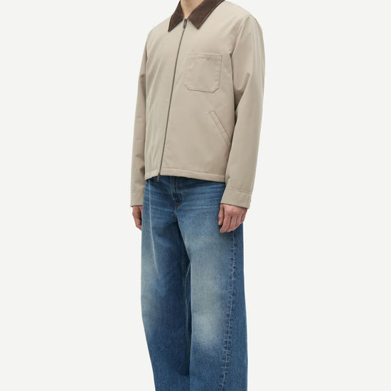 Man wearing a beige jacket with a brown collar by samsoe samsoe on a white background left side view