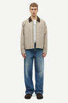 Man wearing a beige jacket with a brown collar by samsoe samsoe on a white background full outfit